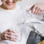 Jangan Remehkan! Ini Manfaat Air Putih Bagi Kesehatan Tubuh Manusia Ilustrasi Wanita sedang menuangkan air ke dalam gelas