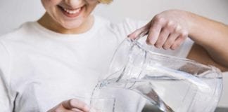 Jangan Remehkan! Ini Manfaat Air Putih Bagi Kesehatan Tubuh Manusia Ilustrasi Wanita sedang menuangkan air ke dalam gelas