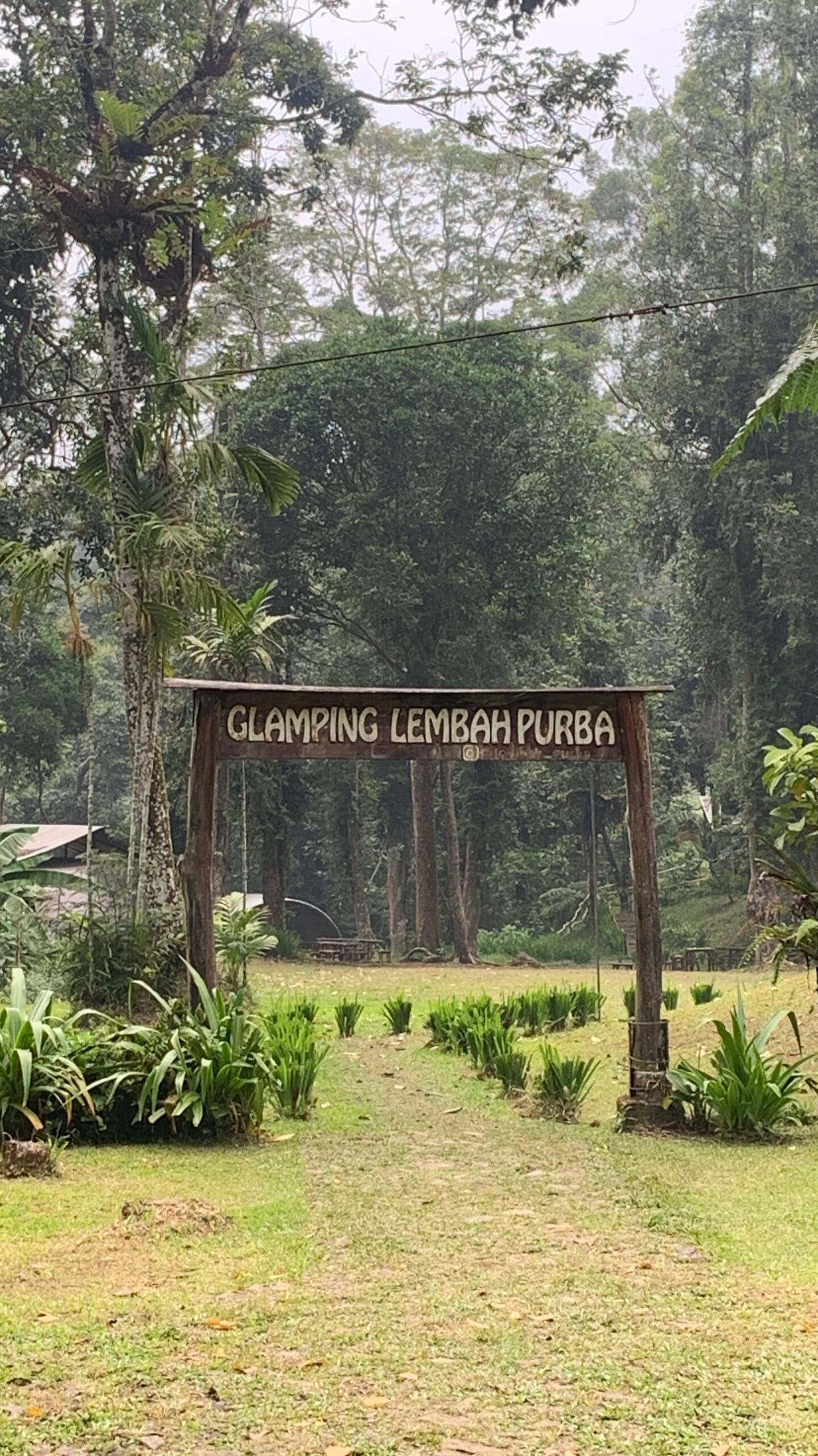 Wooden entrance gate to Lembah Purba glamping campsite in Sukabumi